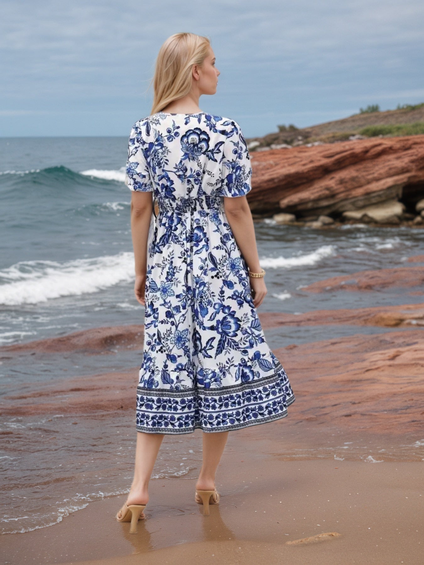 Womens Floral V-Neck Dress worn by a model on sandy beach, showcasing vibrant floral print and beachy style.
